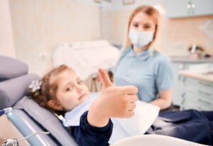 Dentista y niña sonriendo en la primera visita al dentista