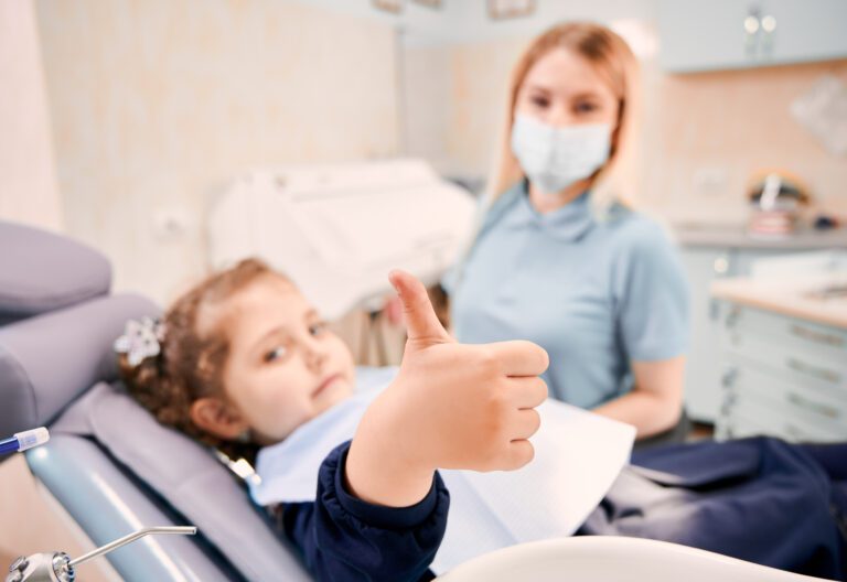Dentista y niña sonriendo en la primera visita al dentista